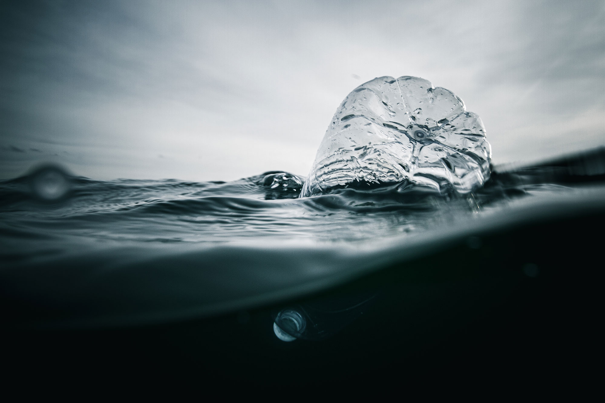 Dark image of a clear plastic bottle floating on the surface of water
