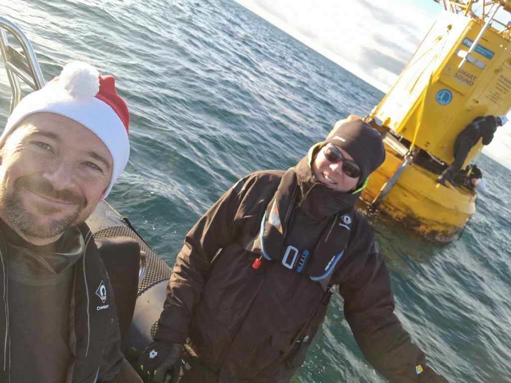 John ’Mac’ McDonald (left) with Jani Pewter (right), and Professor James Fishwick working on the L4 data buoy behind them, pictured shortly before receiving the Mayday call
